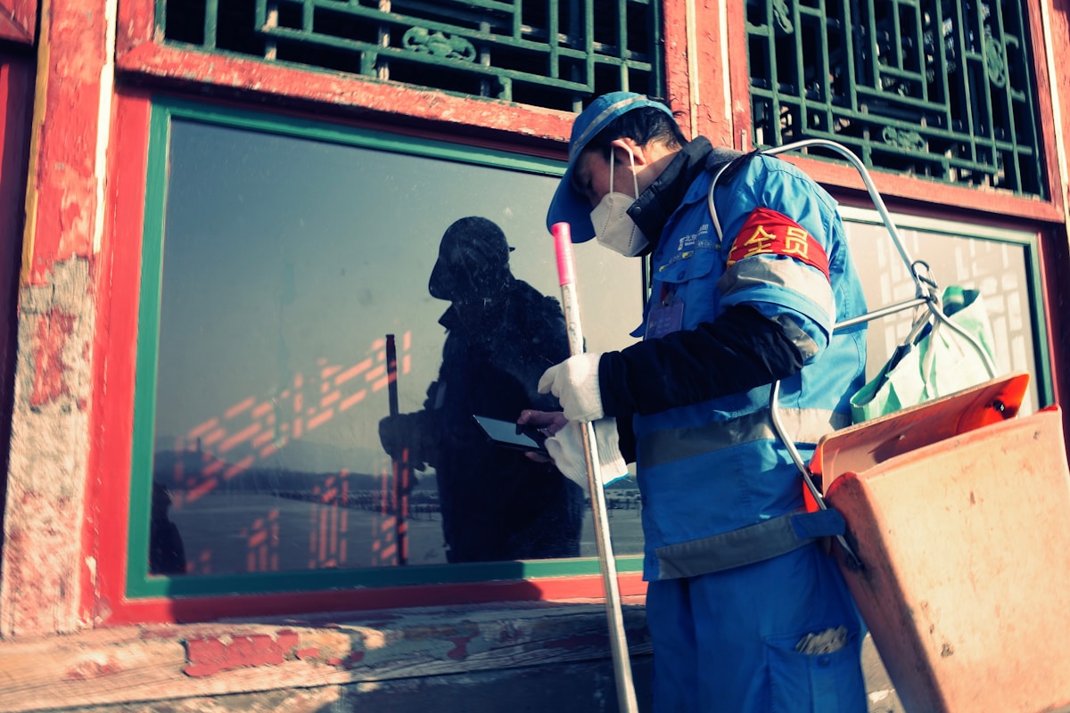 Uniformed cleaning worker servicing a window at a work location.